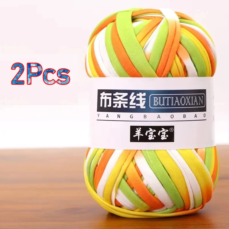A bundle of two skeins of soft chunky t-shirt yarn in various shades of green, orange, and white.