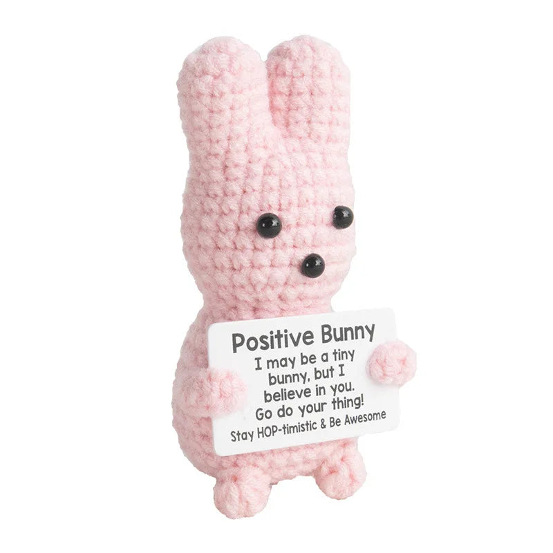 A handmade crochet bunny doll in pink with black eyes, used as a desk or home decor item.