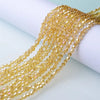 A close-up of gold-colored faceted glass beads strung together for jewelry making.
