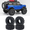 Un véhicule RC crawler bleu avec de grandes pneus en caoutchouc noir et un accessoire rouge sur le toit.