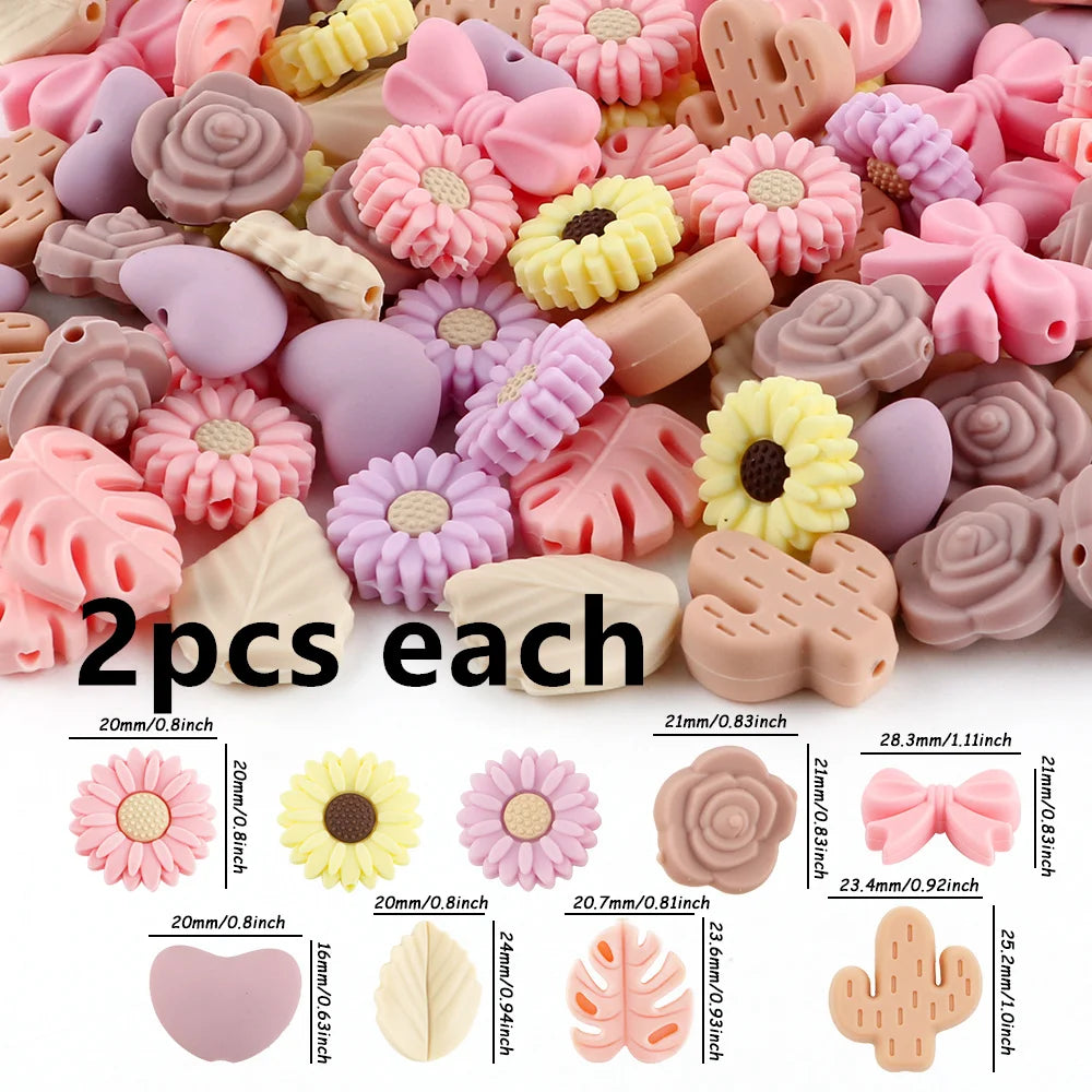 A collection of pink, purple, and yellow silicone flower and leaf beads for jewelry making.