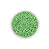 A clear plastic container filled with small, round, light green glass seed beads for jewelry making.