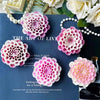 Pink and white flower silicone molds for candle, soap, and resin crafting displayed on a dark blue surface.
