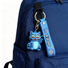 A blue K-pop themed keychain featuring an anime demon hunter collectible doll attached to a dark blue backpack.