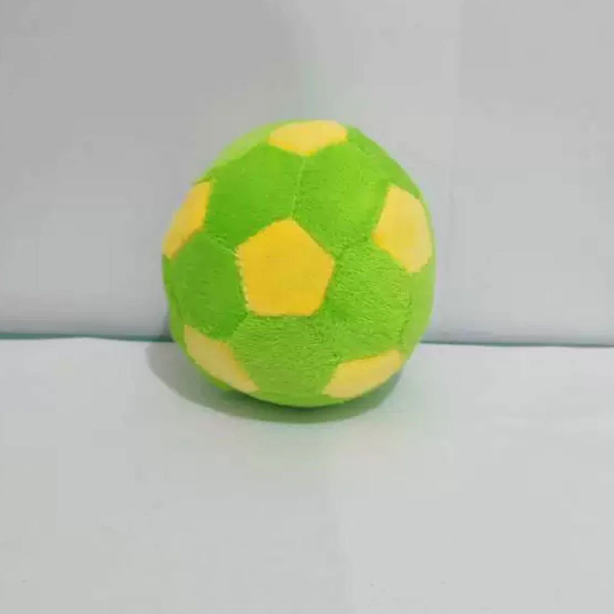 A single handmade crochet hacky sack ball in bright lime green with yellow accents.