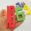A hand holds a red wooden number building block and a green wooden number building block among other colored blocks.