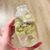 A hand holds a clear bottle filled with liquid and sliced kiwi, labeled Chiboki drink cup toy.