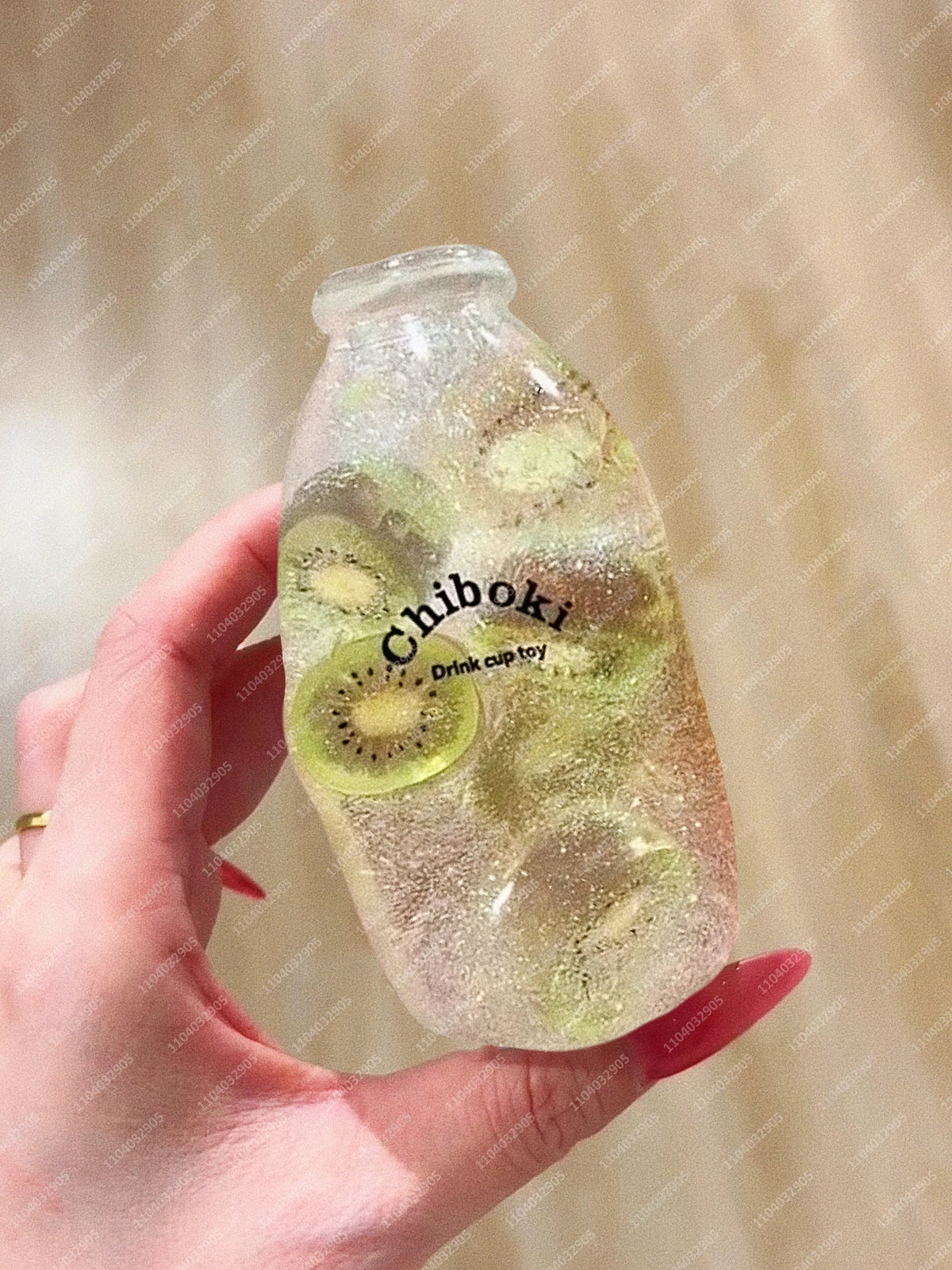 A hand holds a clear bottle filled with liquid and sliced kiwi, labeled Chiboki drink cup toy.