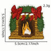 A hand-stitched embroidery patch depicting a festive scene with red bows, green foliage, and a yellow-lit fireplace.