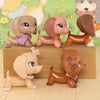 A set of three dachshund bobblehead figurines in various shades of brown and tan, displayed on a wooden block.