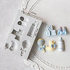 A white silicone cake molds set featuring various baby-themed shapes including a stroller, bottle, pacifier, and various smal