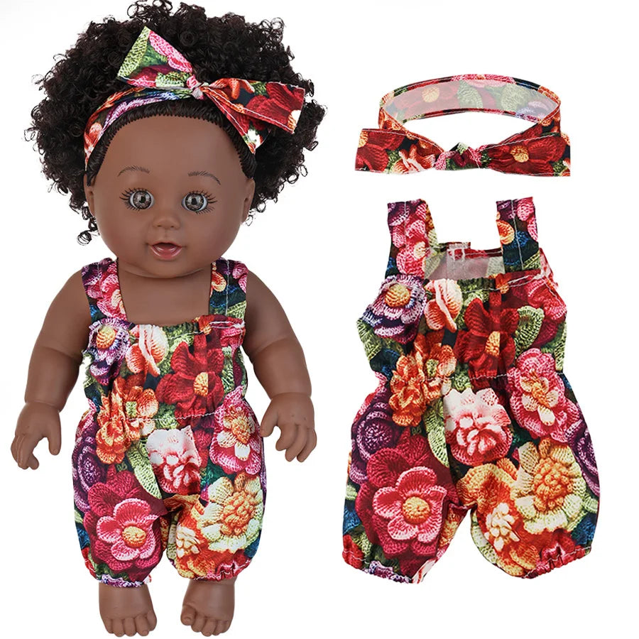 A realistic 12-inch African American baby doll wearing a floral patterned outfit with a bow in her hair.
