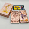 A box of gold foil tarot cards with a rose pink oracle finish and a deck of Knight of Cups tarot cards.
