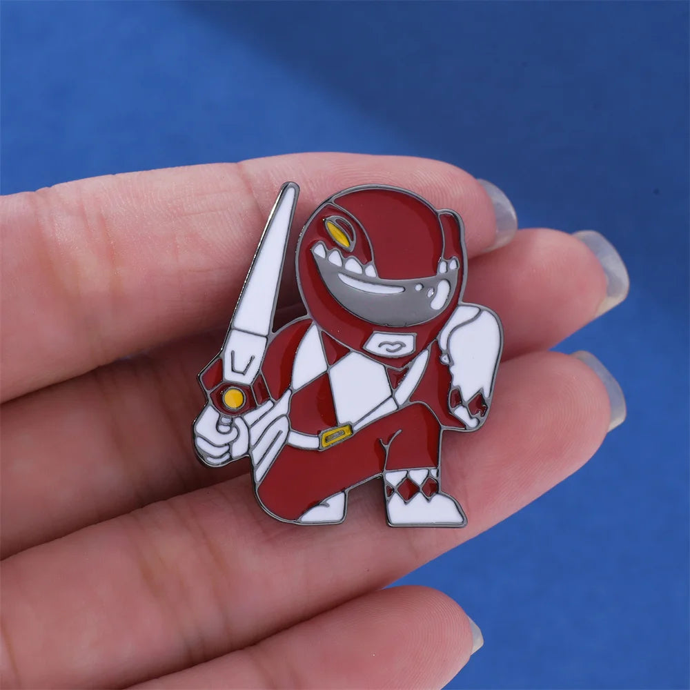 An enamel pin featuring a dinosaur ranger battle suit and helmet design held in a hand against a blue background.