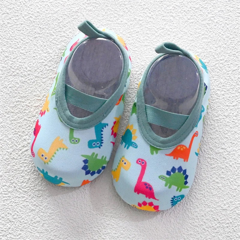 A pair of colorful baby barefoot water shoes featuring various dinosaur and animal patterns.