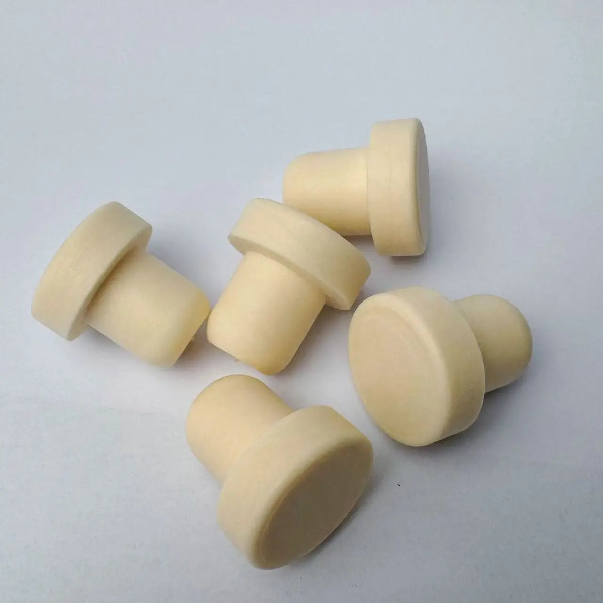 A set of ten beige reusable T-shaped wine bottle stoppers arranged on a white surface.