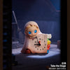 A blind box collectible figure of a smiling baby with blue eyes and light pink clothing sitting on a surface.