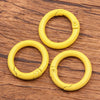 A pile of ten yellow metal O-ring spring clasps for DIY jewelry and keychains resting on a wooden surface.