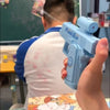 A person holds a light blue two-way press and spray water gun against a blurred background.