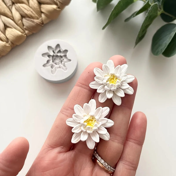 Eine Hand hält mehrere weiße Silikon-Blumenharzgießformen für Bastelarbeiten vor weißem Hintergrund.