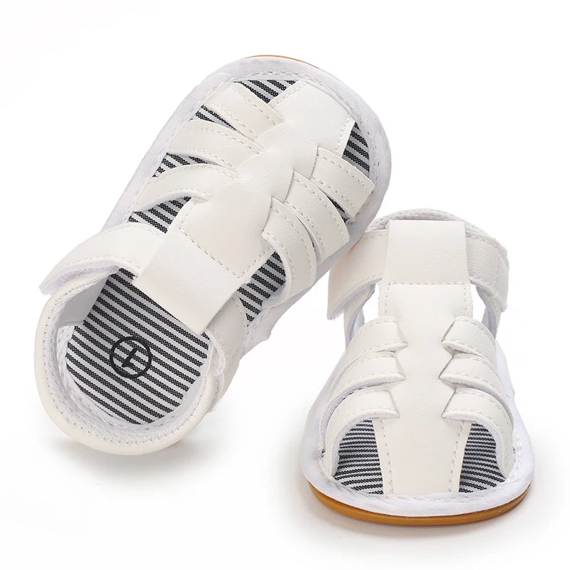 A pair of white baby first walker sandals with black stripes and a soft anti-slip sole.