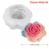 A white silicone flower mold with a pink rose design and a separate pink floral silicone flower.
