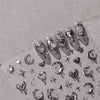 A collection of silver and black gothic nail art stickers featuring skulls, hearts, stars, and other decorative elements.