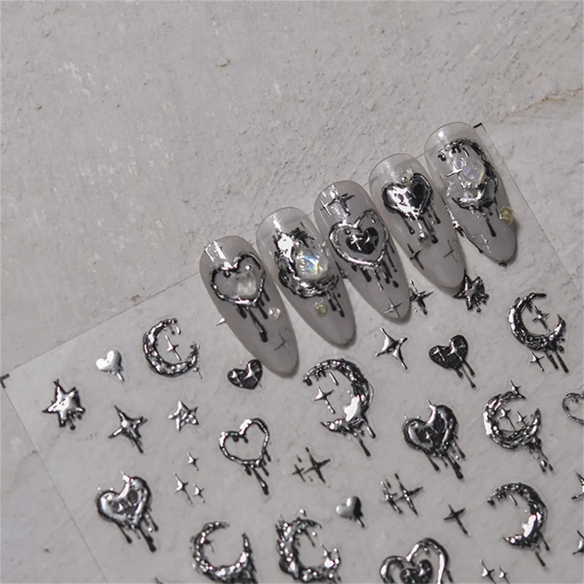 A collection of silver and black gothic nail art stickers featuring skulls, hearts, stars, and other decorative elements.