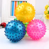 A set of three brightly colored inflatable sensory balls in yellow, blue, and pink resting on a white surface.