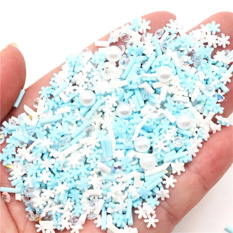 A handful of polymer clay slices in light blue and white snowflake designs is held in a hand.