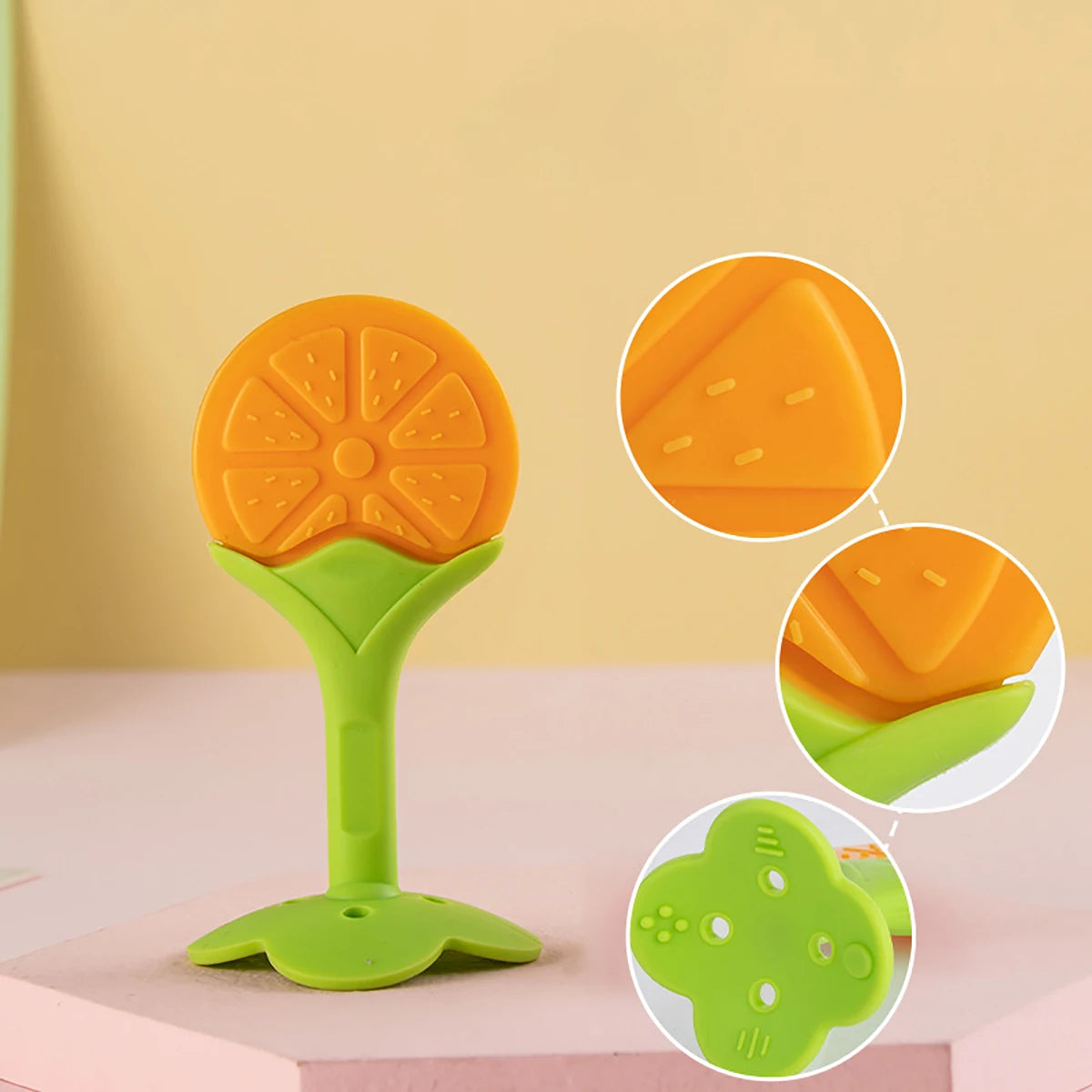 A bright orange silicone fruit-shaped baby teether with a green handle and base.