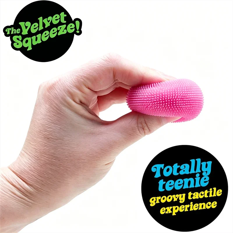 A hand holds a pink silicone fuzz ball stress relief toy, demonstrating its texture and size.