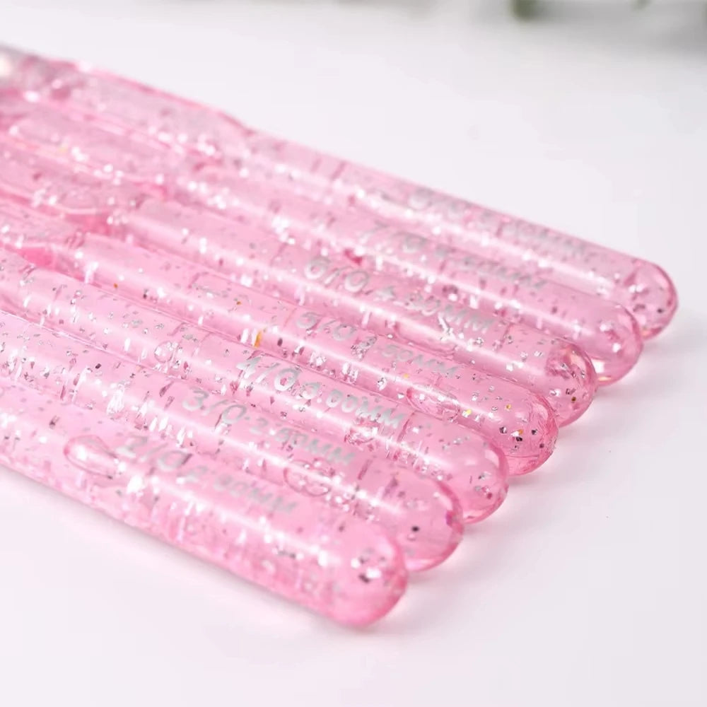 A close-up view of a 7-piece pink aluminum crochet hook set with color-coded handles arranged diagonally.