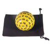 A yellow 100-sided polyhedral die is resting in a dark brown storage bag.