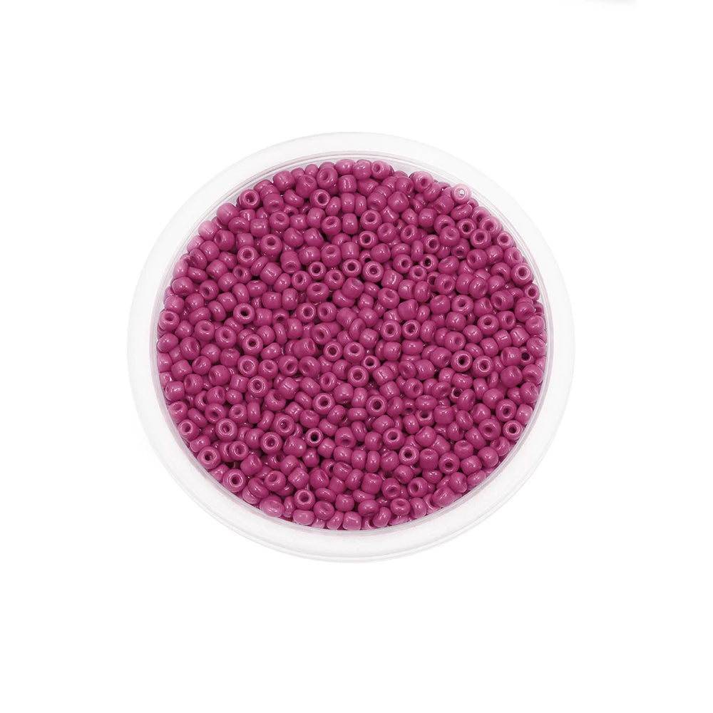 A clear container filled with small, round, purple glass seed beads for jewelry making.
