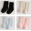Three pairs of baby anti-slip fleece socks in black, cream, and pink.