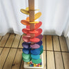 A wooden sensory music tree with colorful, layered discs and a marble run at the base.