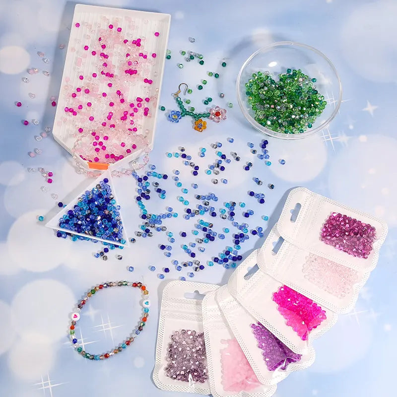 Assortment of faceted crystal glass beads in various colors and shapes scattered on a light blue surface.