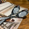 A silver spoon rests on a leather-bound book next to a PU leather drawstring dice bag.