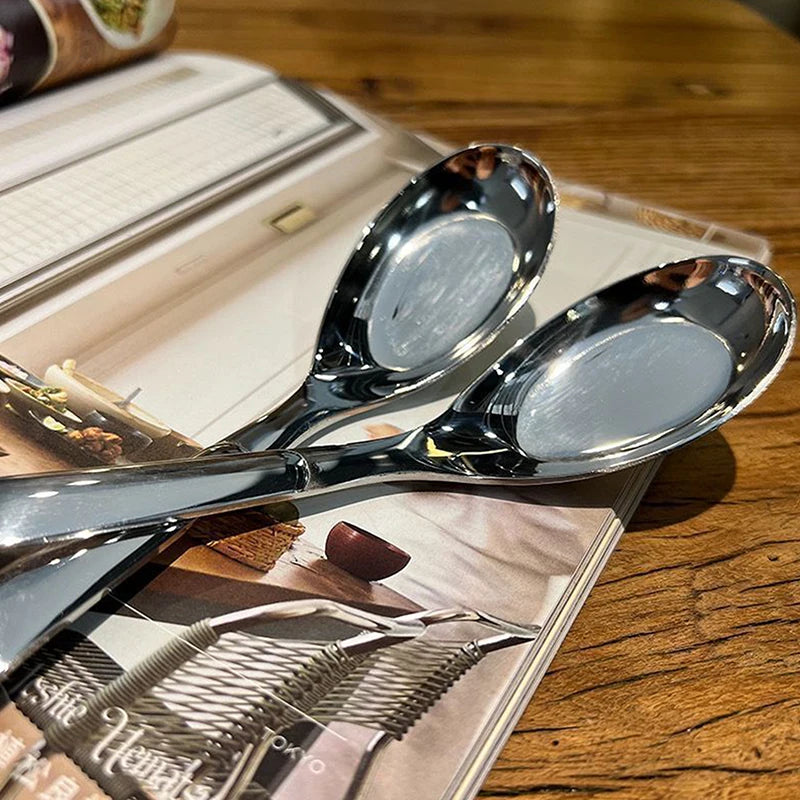 A silver spoon rests on a leather-bound book next to a PU leather drawstring dice bag.