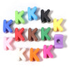 A collection of colorful acrylic letter K beads in various shades including blue, green, black, yellow, and pink.