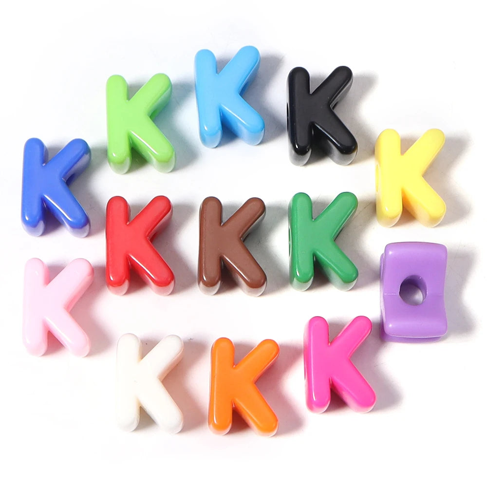A collection of colorful acrylic letter K beads in various shades including blue, green, black, yellow, and pink.