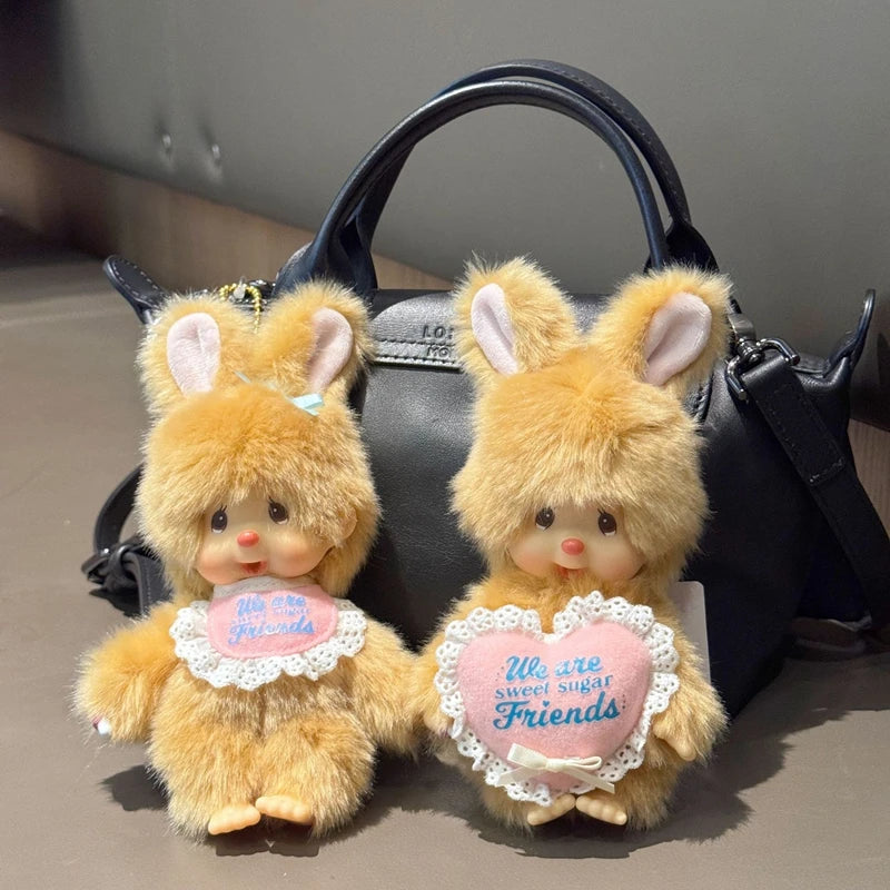 A pair of fluffy orange rabbit plush toys with pink ears and hearts, displayed against a black handbag.