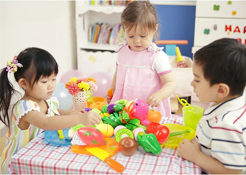 A young child is playing with a pretend play kitchen set featuring colorful fruits and vegetables.