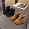 A pair of tan leather winter boots with laces and a brown cuff resting on a gray table.