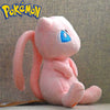 A pink plush doll resembling a Pokémon, with light blue eyes and pink ears, sitting on a surface.
