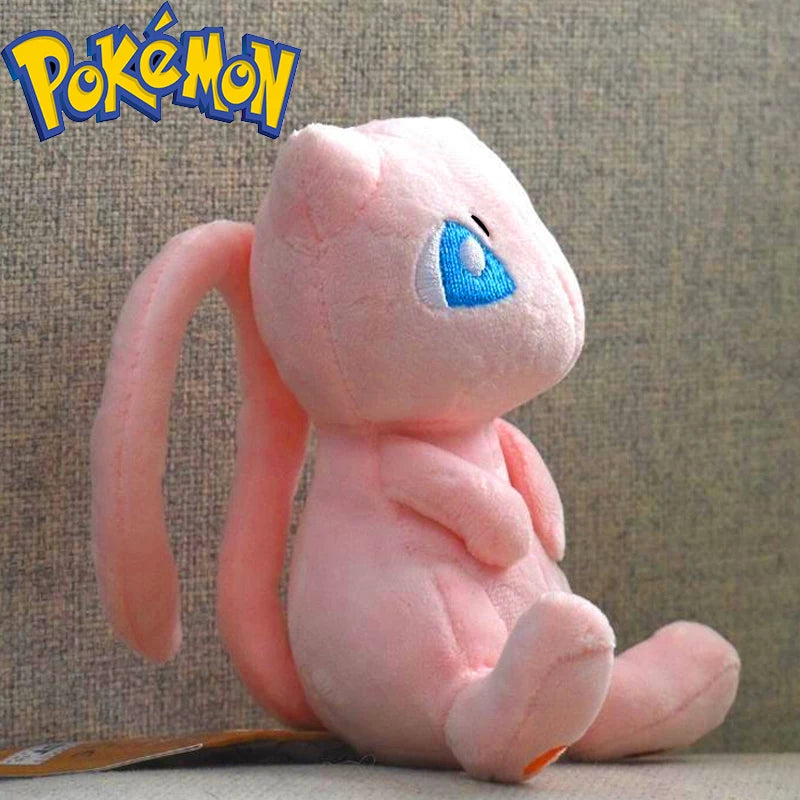 A pink plush doll resembling a Pokémon, with light blue eyes and pink ears, sitting on a surface.