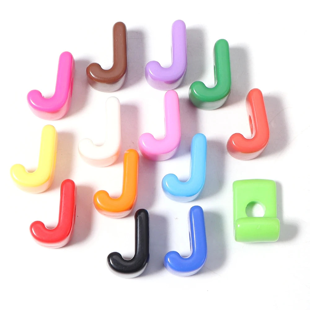 A collection of colorful acrylic alphabet beads shaped like the letter J arranged on a white background.