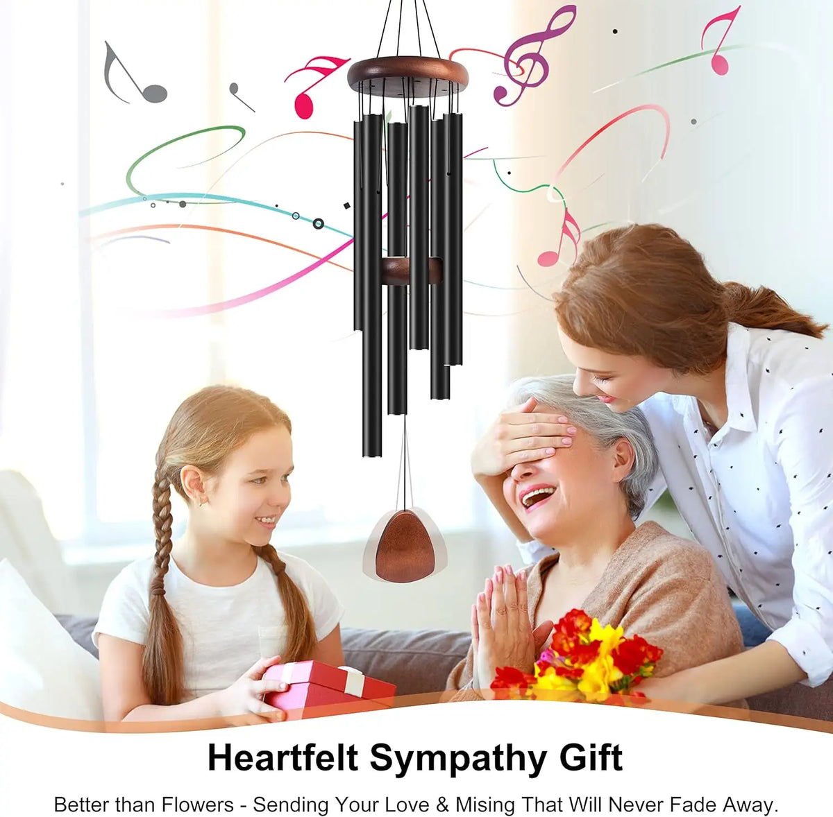A woman gently touches the forehead of an elderly woman while a decorative wind chime hangs above them.