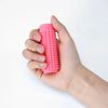 A hand is holding a bright pink spiky sensory keychain for anxiety relief.